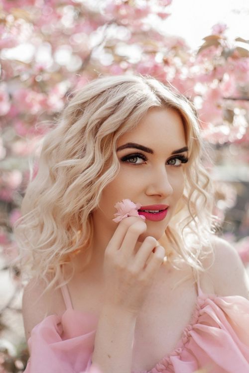 Free Elegant portrait of a blonde woman surrounded by cherry blossoms in spring. Stock Photo