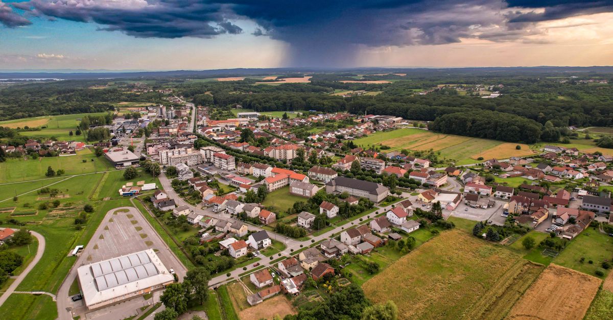 Aerial shot of Garešnica, Croatia, under dramatic storm clouds, showcasing urban and rural landscapes.