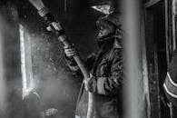 Grayscale Photography of a Fireman Holding a Hose