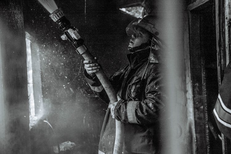 Grayscale Photography Of A Fireman Holding A Hose