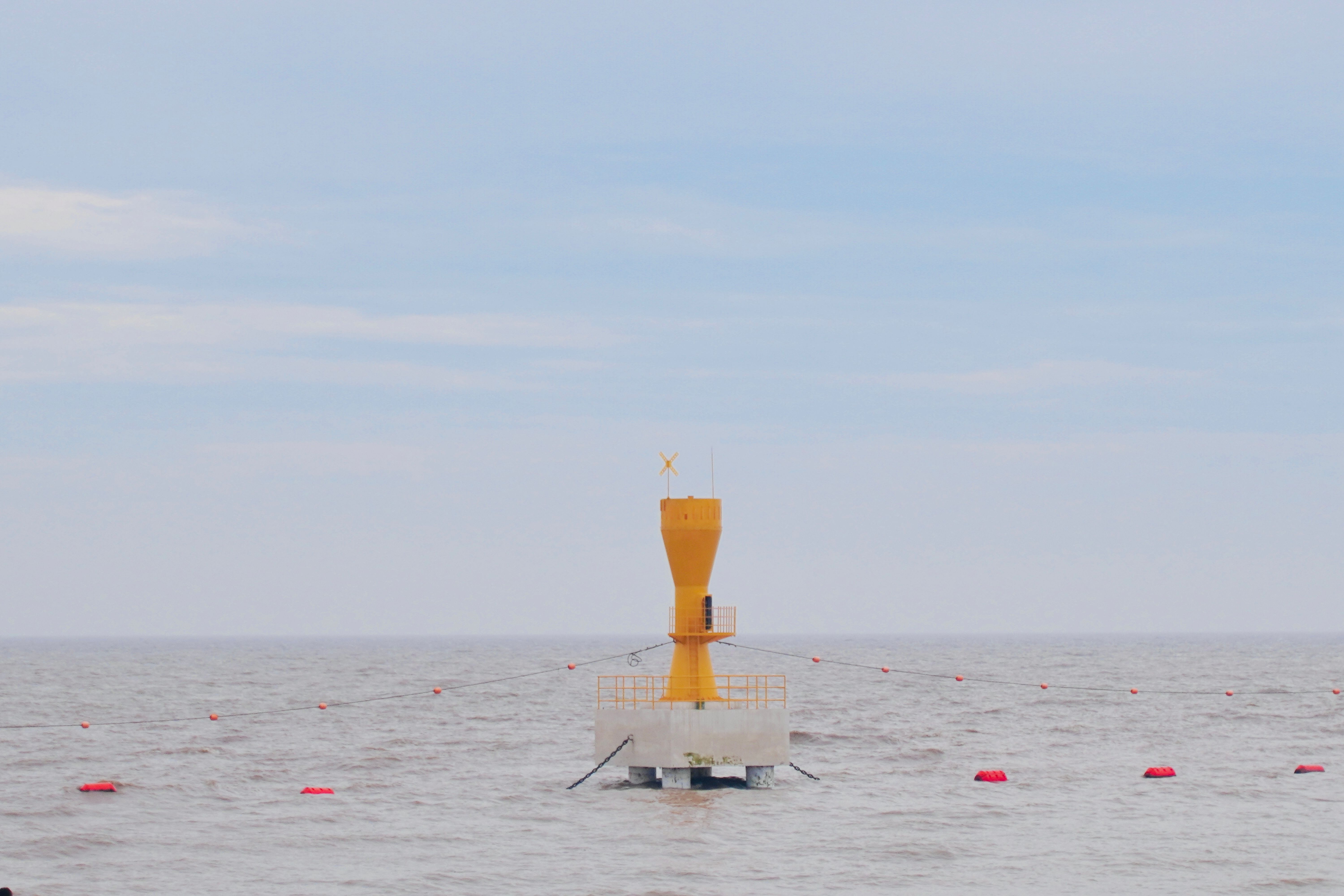 Yellow buoy marking navigation point in the vast, tranquil sea under a clear blue sky.
