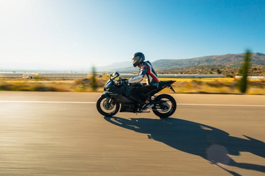 A motorcyclist speeds down an open road under clear skies, showcasing freedom and adventure.