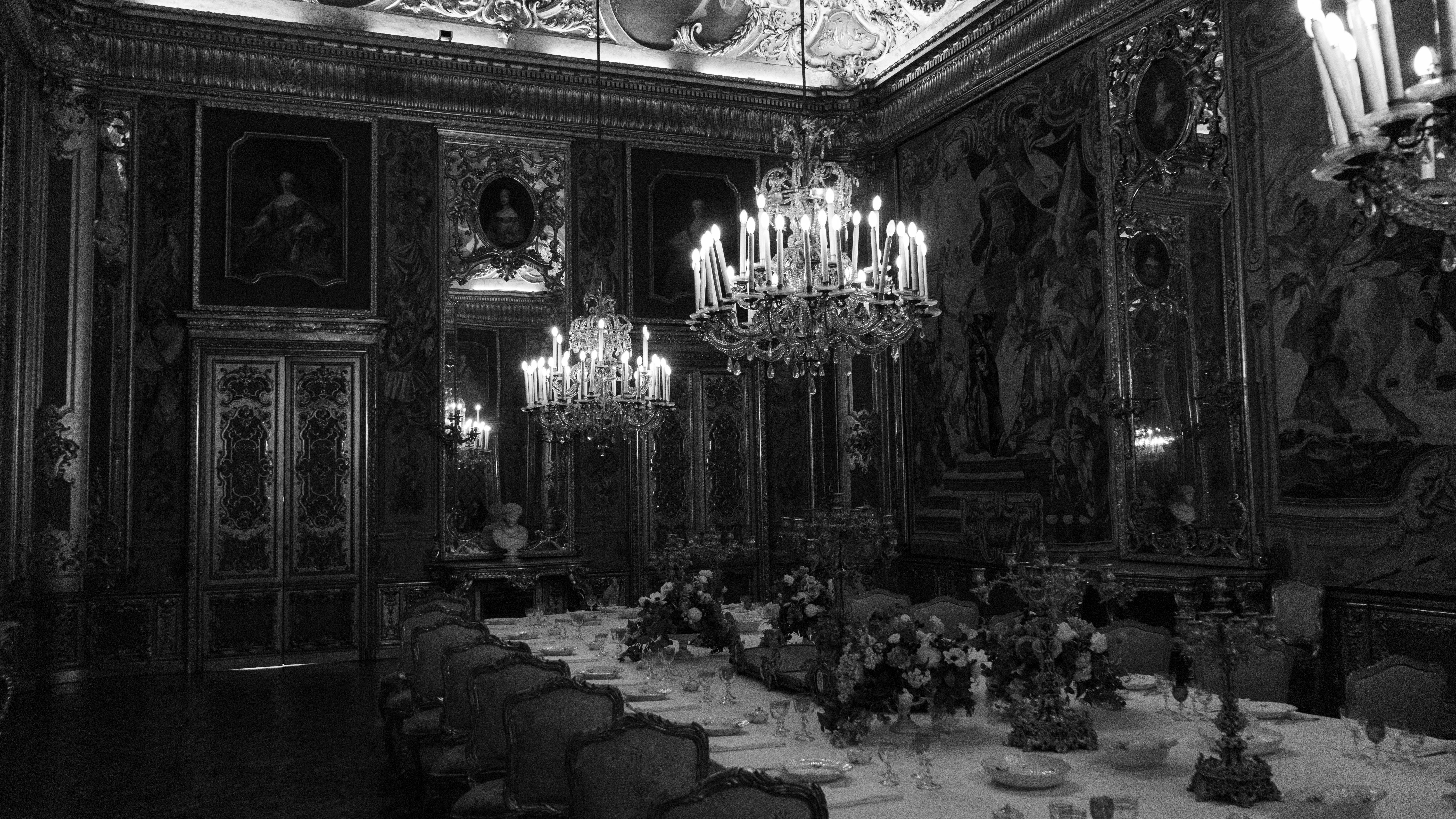 Elegant black and white photo of a grand dining hall with chandeliers and opulent decor, perfect for luxury themes.