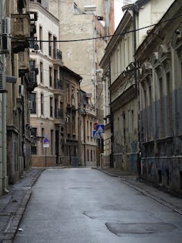 A quiet, narrow urban alley with historic buildings and street signs on a cloudy day.