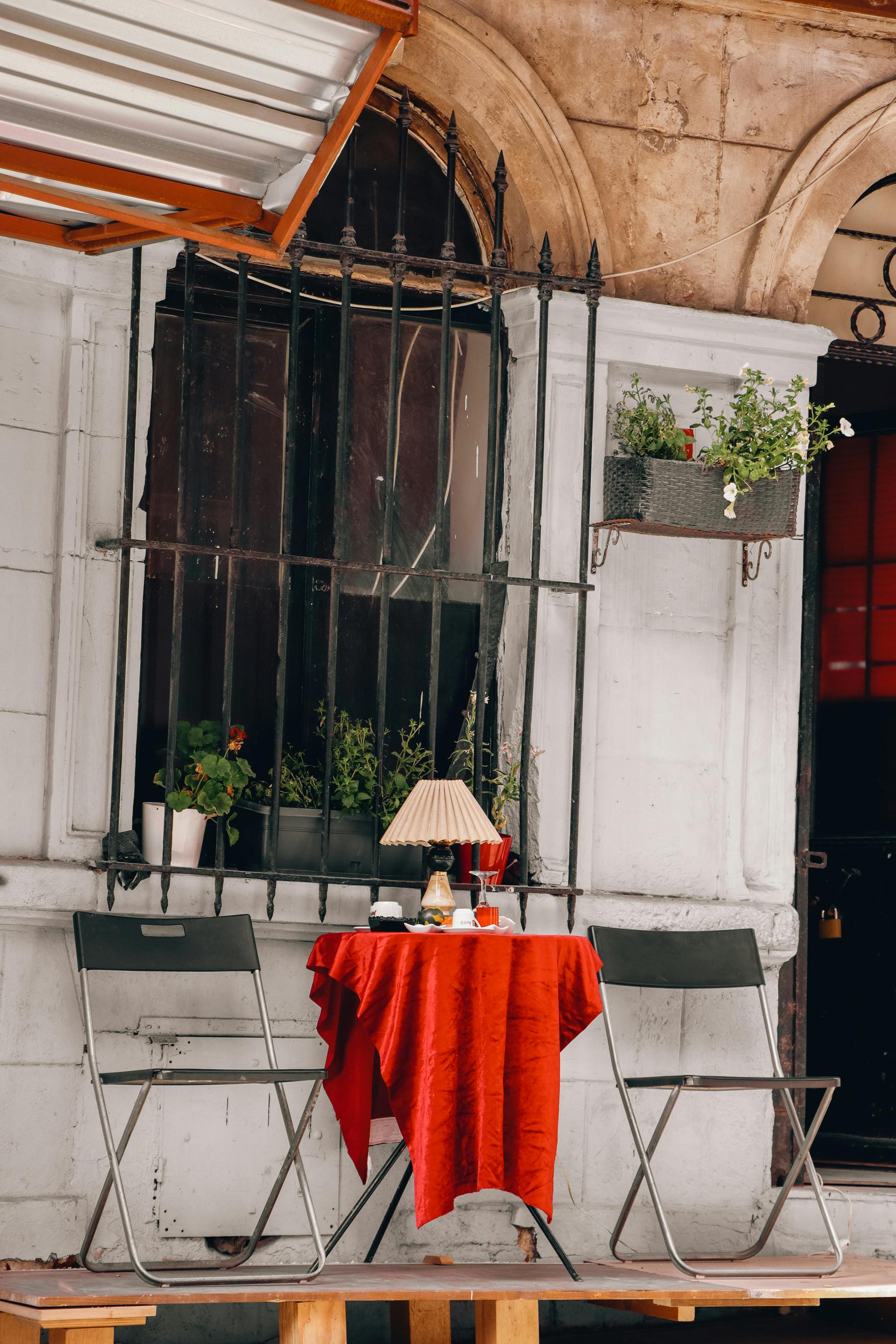 a table and chairs outside a building with red table cloth