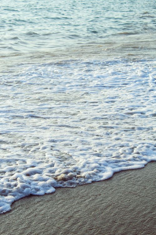 Free Serene beach scene with gentle waves and sandy shore, offering peaceful coastal vibes. Stock Photo