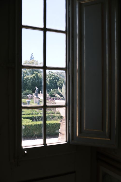 Free A scenic view of a formal garden captured through a vintage window in Queluz, Lisbon. Stock Photo