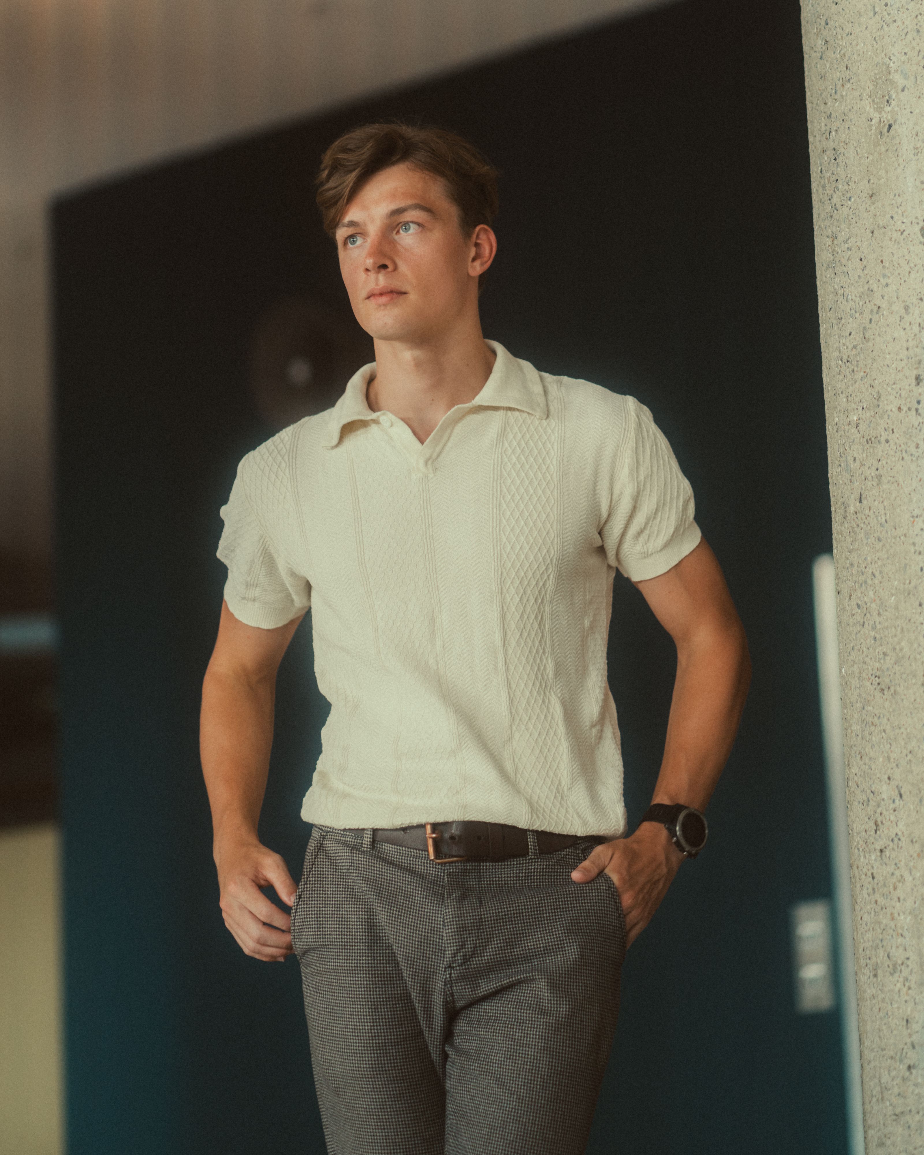Um jovem estiloso em traje casual inteligente posa em ambientes internos, exalando confiança e elegância em Berlim.