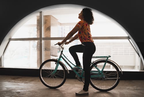 Woman Sitting on Bicycle Inside Building by the Arch Window