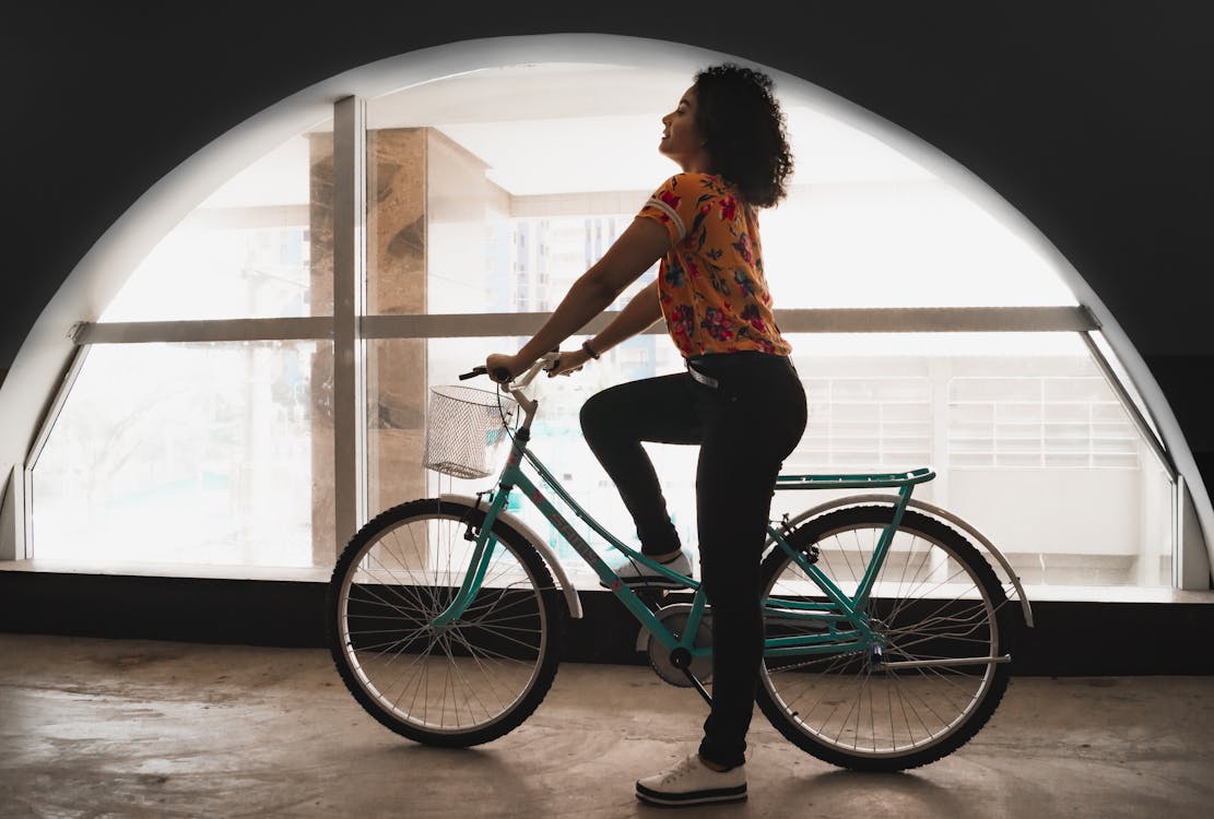 Woman Sitting on Bicycle Inside Building by the Arch Window Free