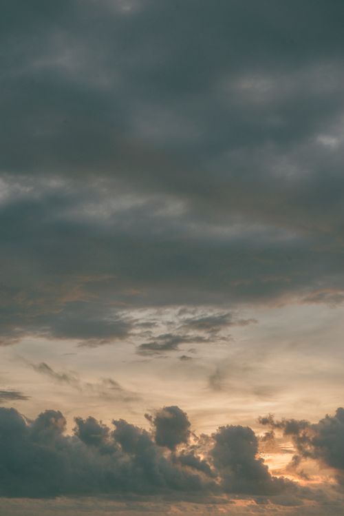 Free A serene view of clouds backlit by a golden sunset, evoking a peaceful and heavenly atmosphere. Stock Photo