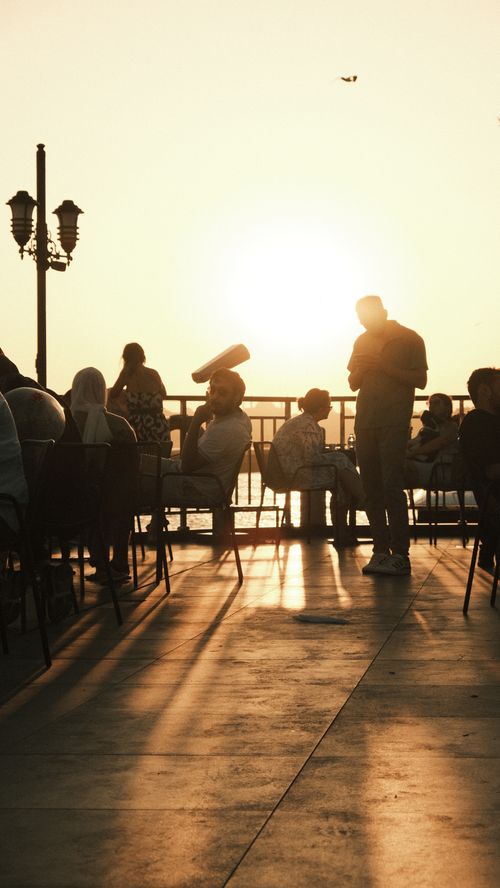 Free People enjoying a serene sunset at a seaside café in Istanbul, creating beautiful silhouettes. Stock Photo
