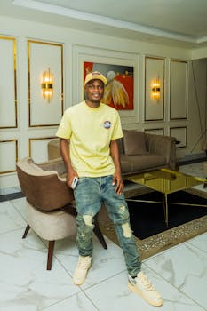 Fashionable young man posing in stylish living room setting with modern decor.