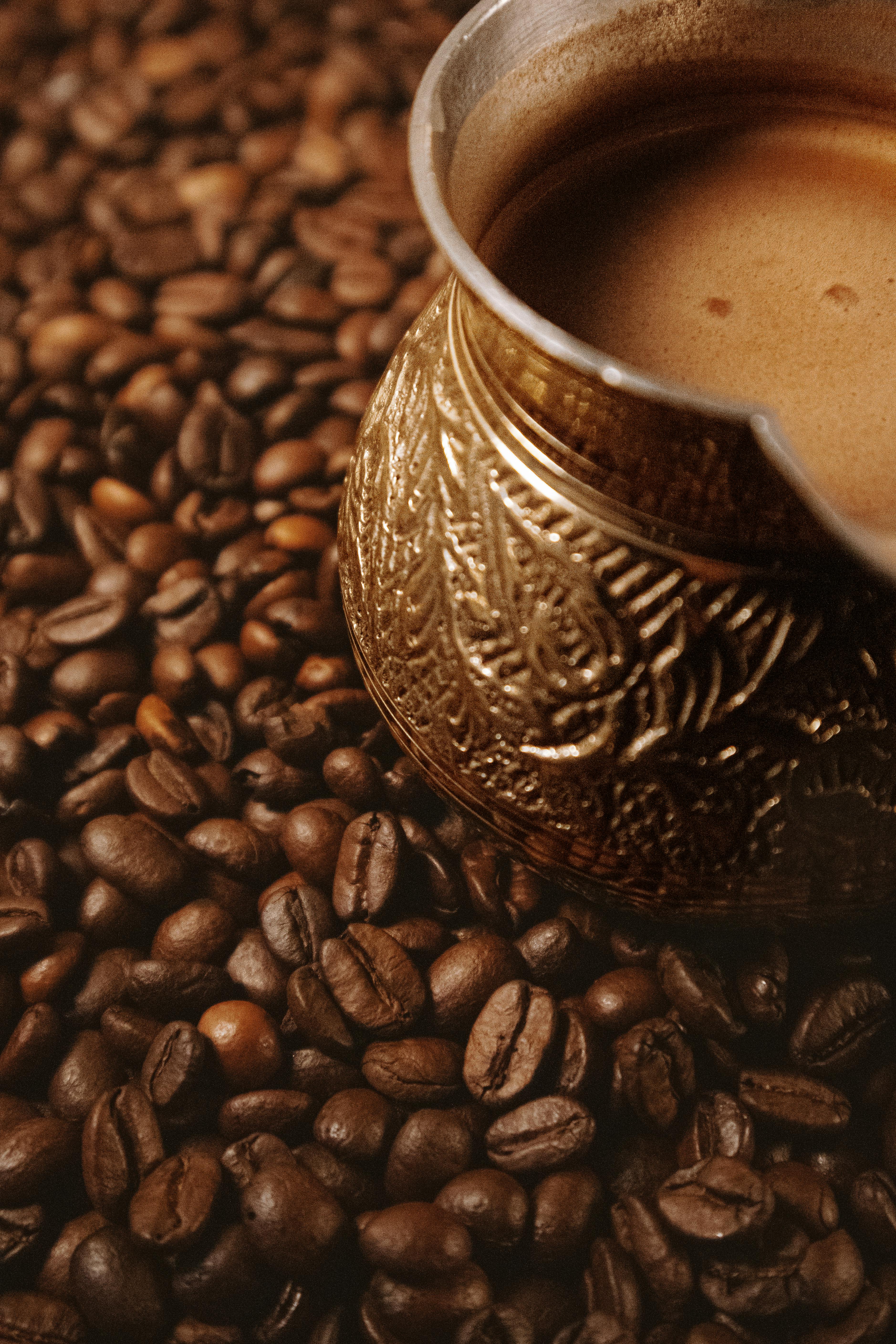Intricate Turkish coffee pot nestled among freshly roasted coffee beans, evoking warmth and tradition.
