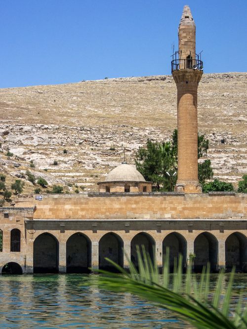 Free A picturesque view of a historic minaret and mosque reflecting on a river in Halfeti, Turkey. Stock Photo