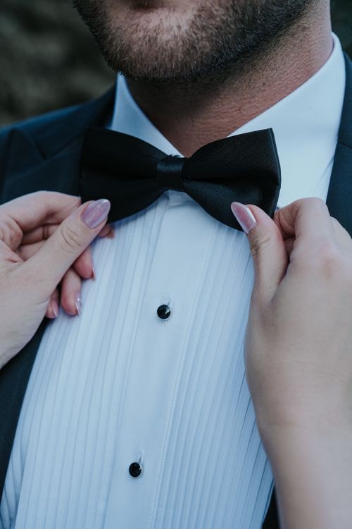 Free Hands adjusting a man's black bow tie on a formal white shirt. Stock Photo