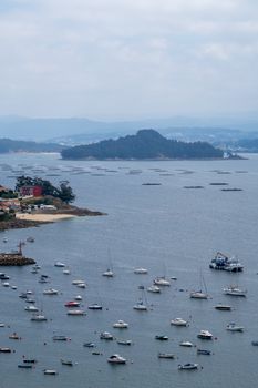 A beautiful aerial view of boats in a harbor with distant islands and cloudy skies.