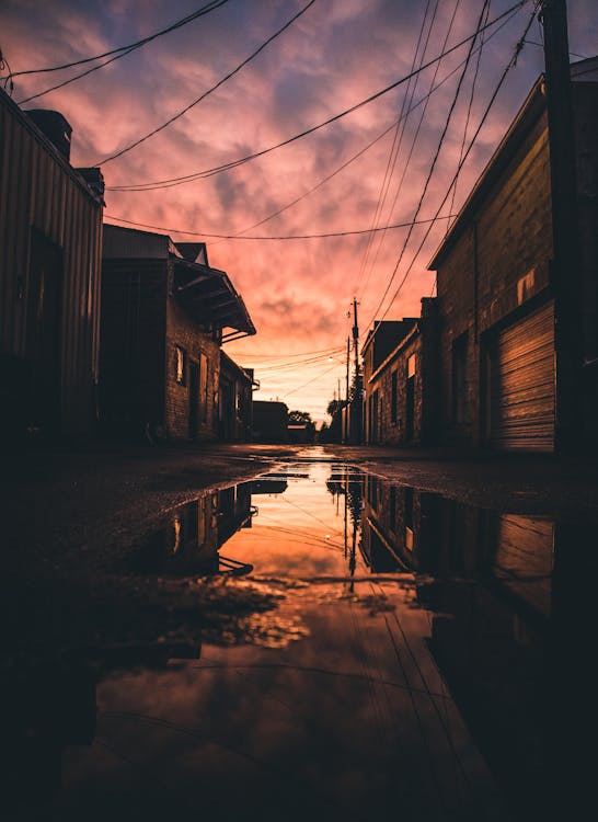 Free Water Puddle Between Buildings During Golden Hour Stock Photo