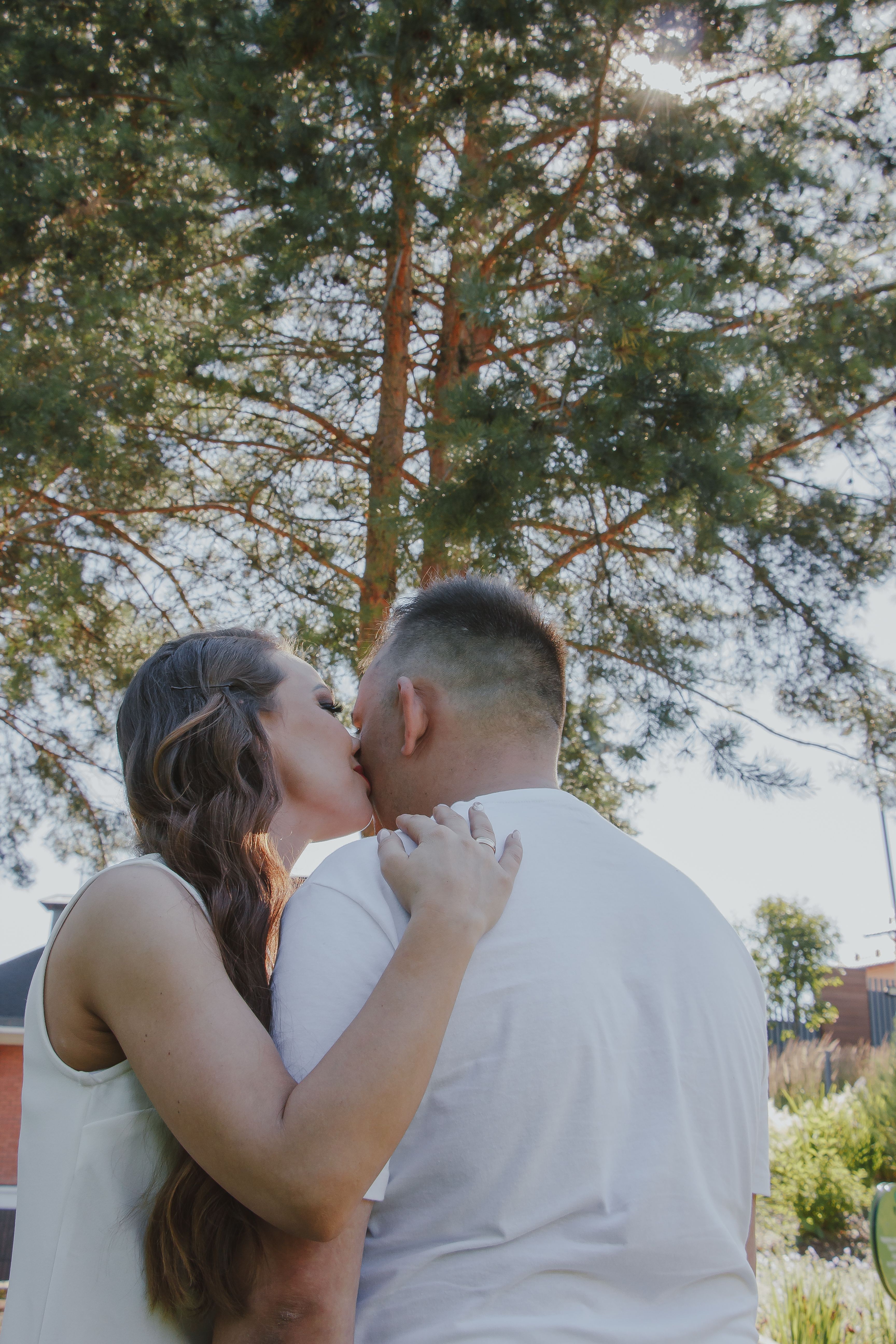 A couple kissing in front of a tree · Free Stock Photo