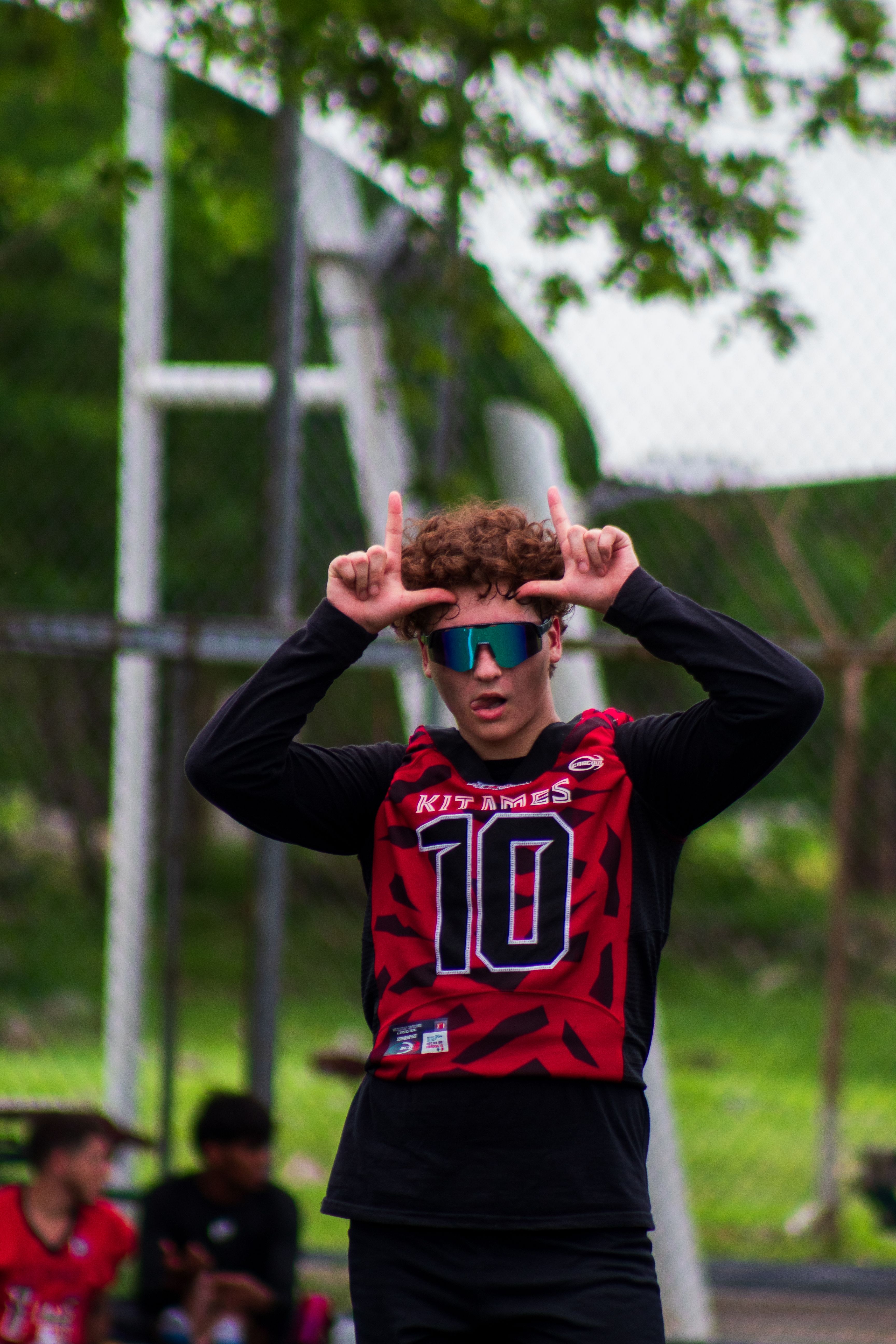 Teen athlete posing with sunglasses outdoors in Mérida, showcasing vibrant sportswear.