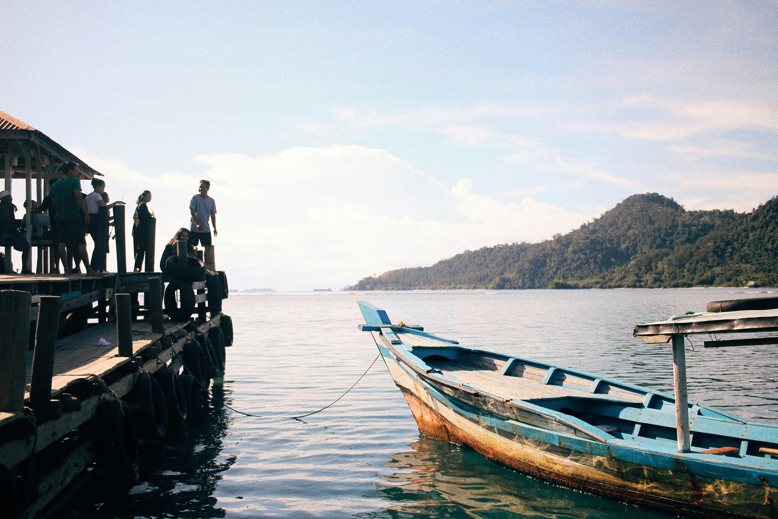 people standing on a pier with a moored boat