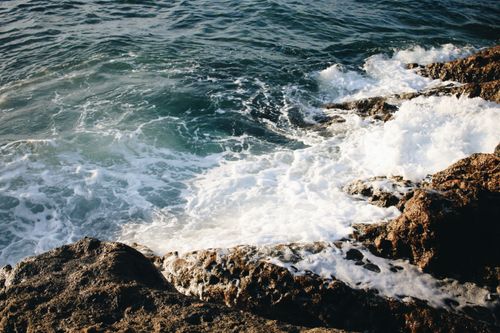 Free A vibrant seascape with ocean waves crashing against a rocky coast under daylight. Stock Photo