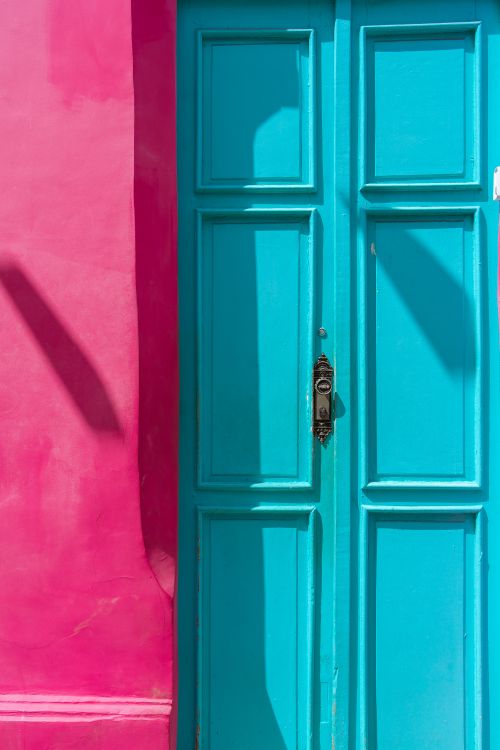 Free A striking image of a bright light blue door set against a vivid pink wall. Stock Photo