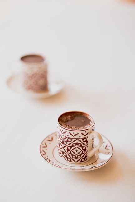 Close-up of ornate coffee cups featuring ethnic design, filled with black coffee.
