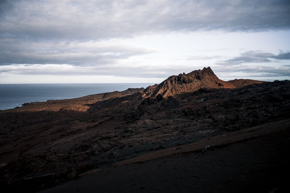 Terreno volcánico de Galápagos al ocaso con rocas oscuras y horizonte oceánico