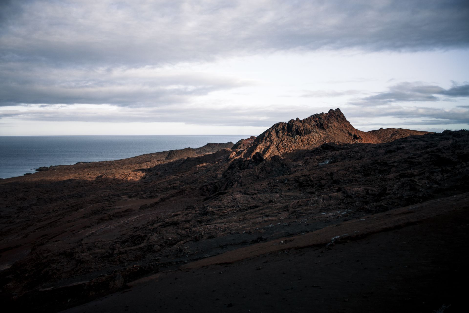 Majestic Galapagos terrain at sunset, highlighting volcanic rocks and ocean horizon.