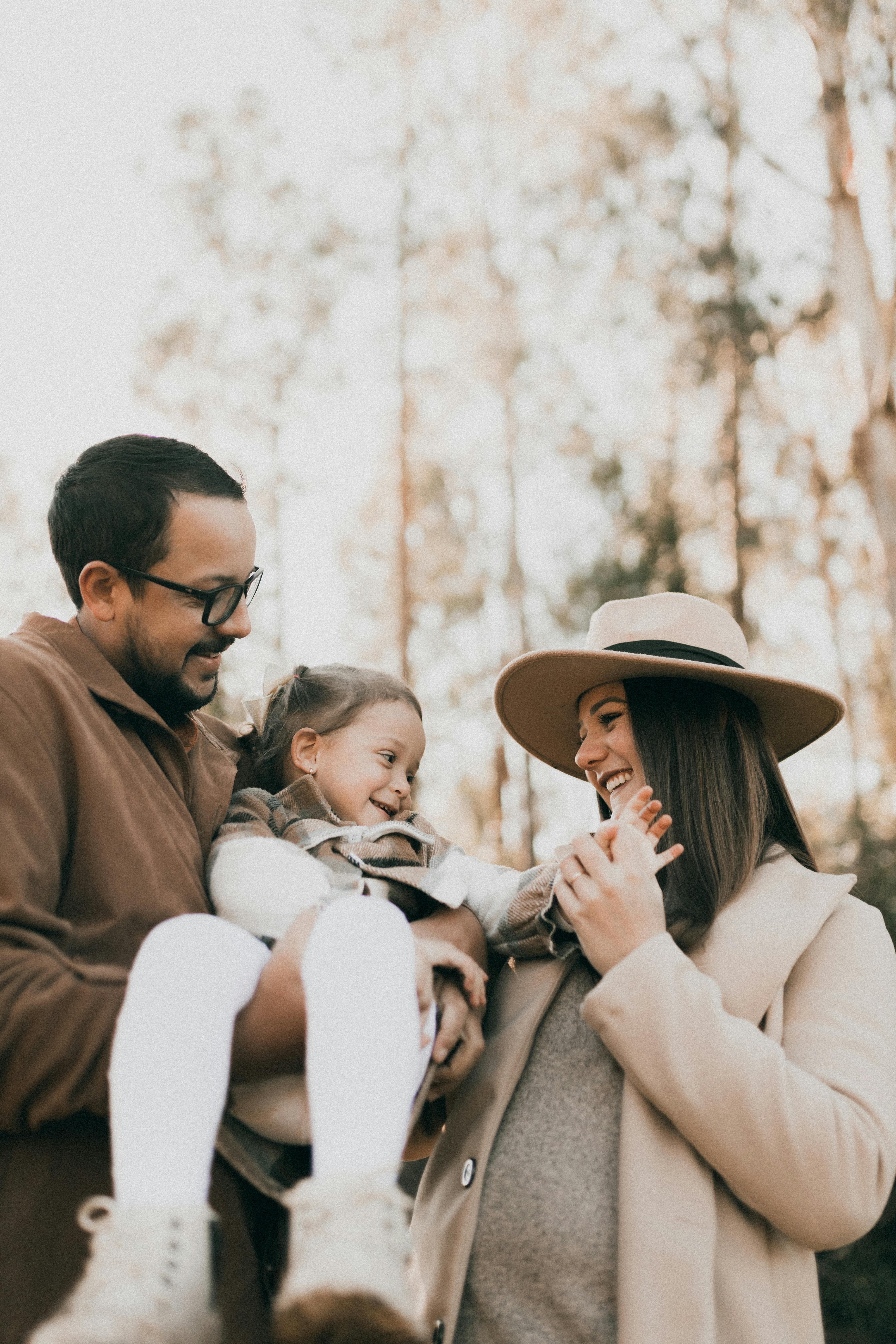 a family with a little daughter posing in a forest in autumn