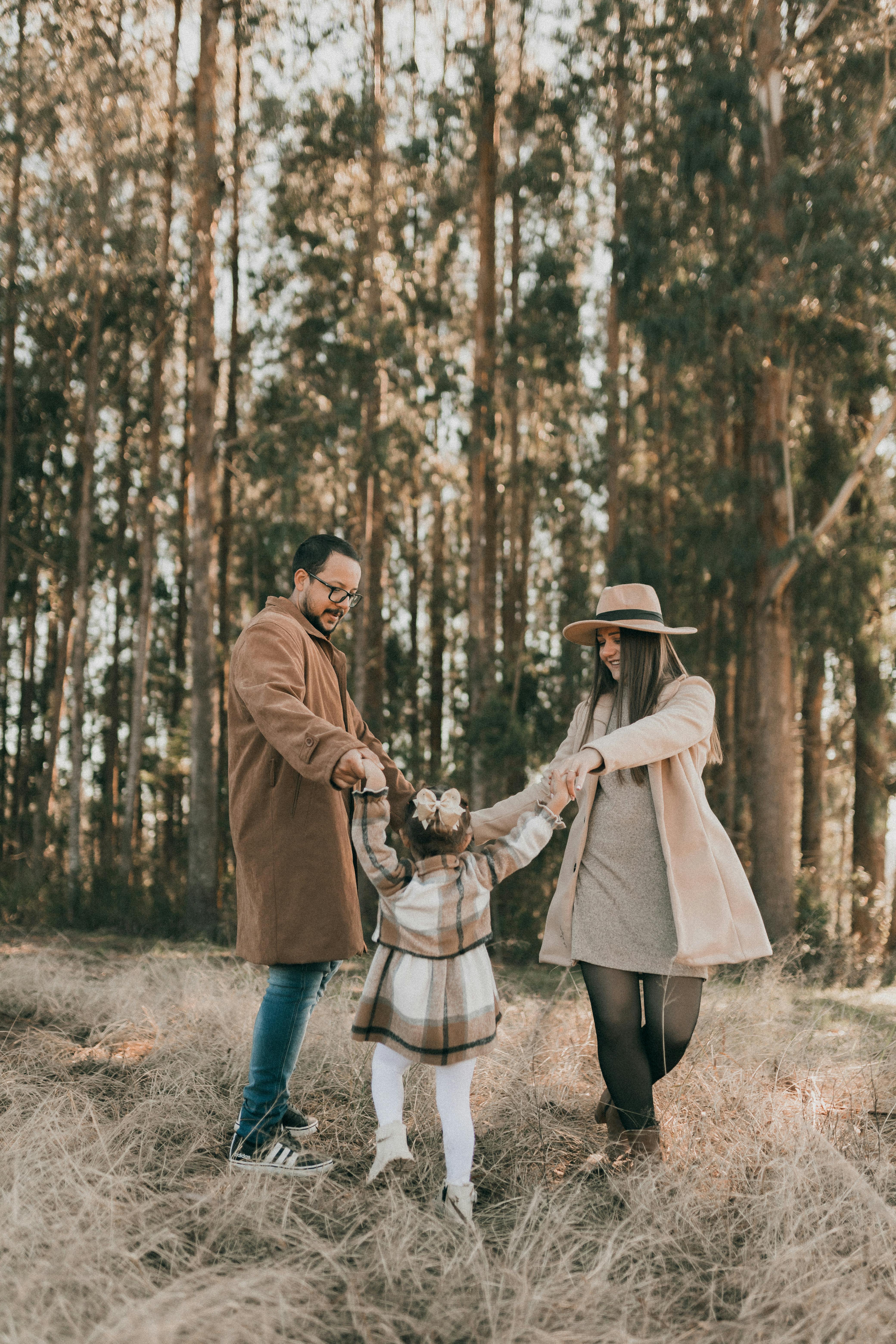 a family with a little daughter dancing in a forest in autumn