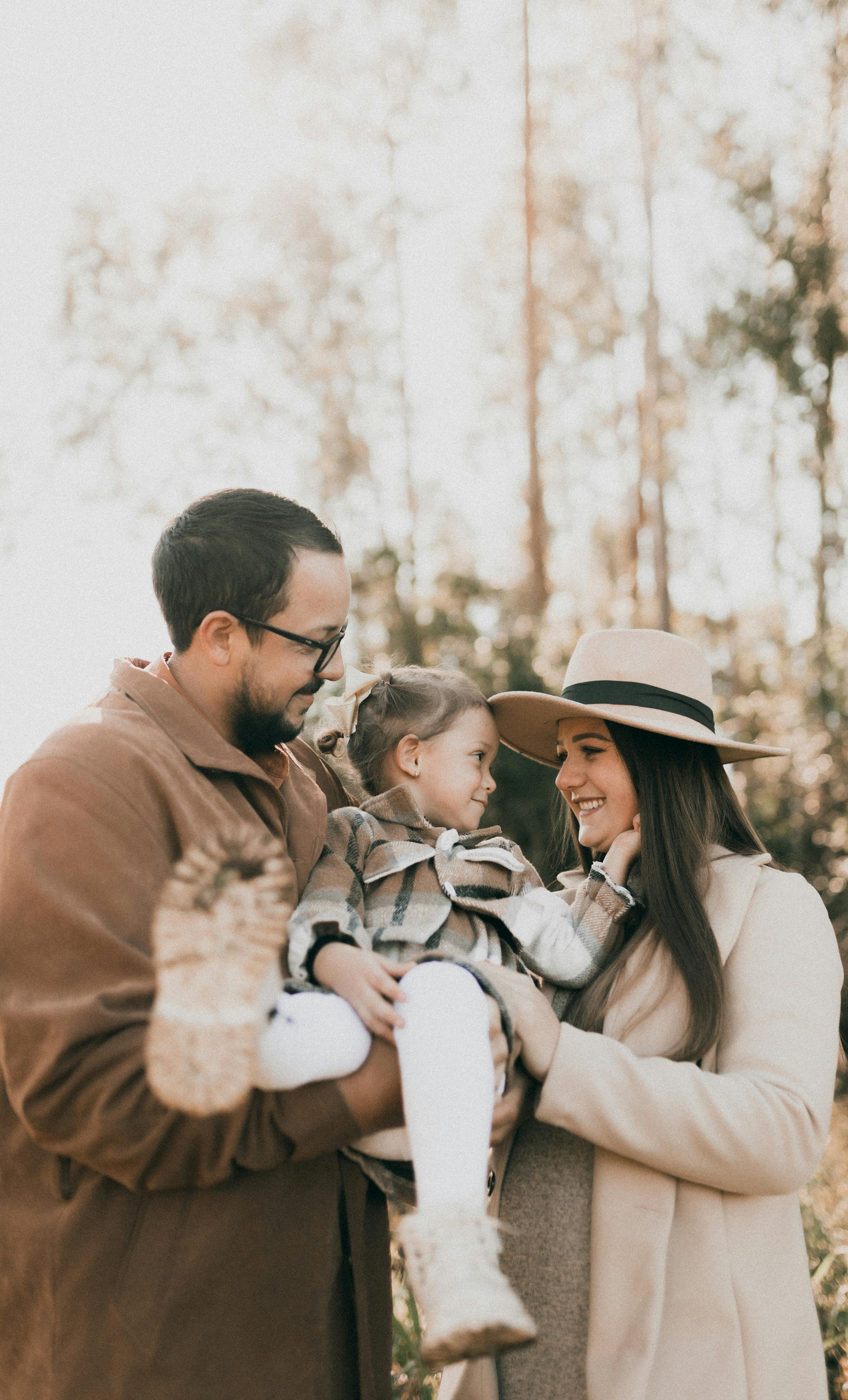 a family with a little daughter posing in a forest in autumn