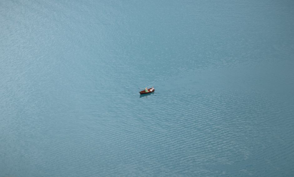 Aerial view of a lone rowboat on the serene blue waters of Lake Bled, Slovenia.