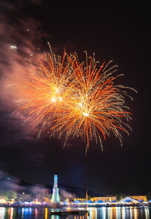 Free Colorful fireworks illuminate the night sky above a city waterfront during a festival celebration. Stock Photo