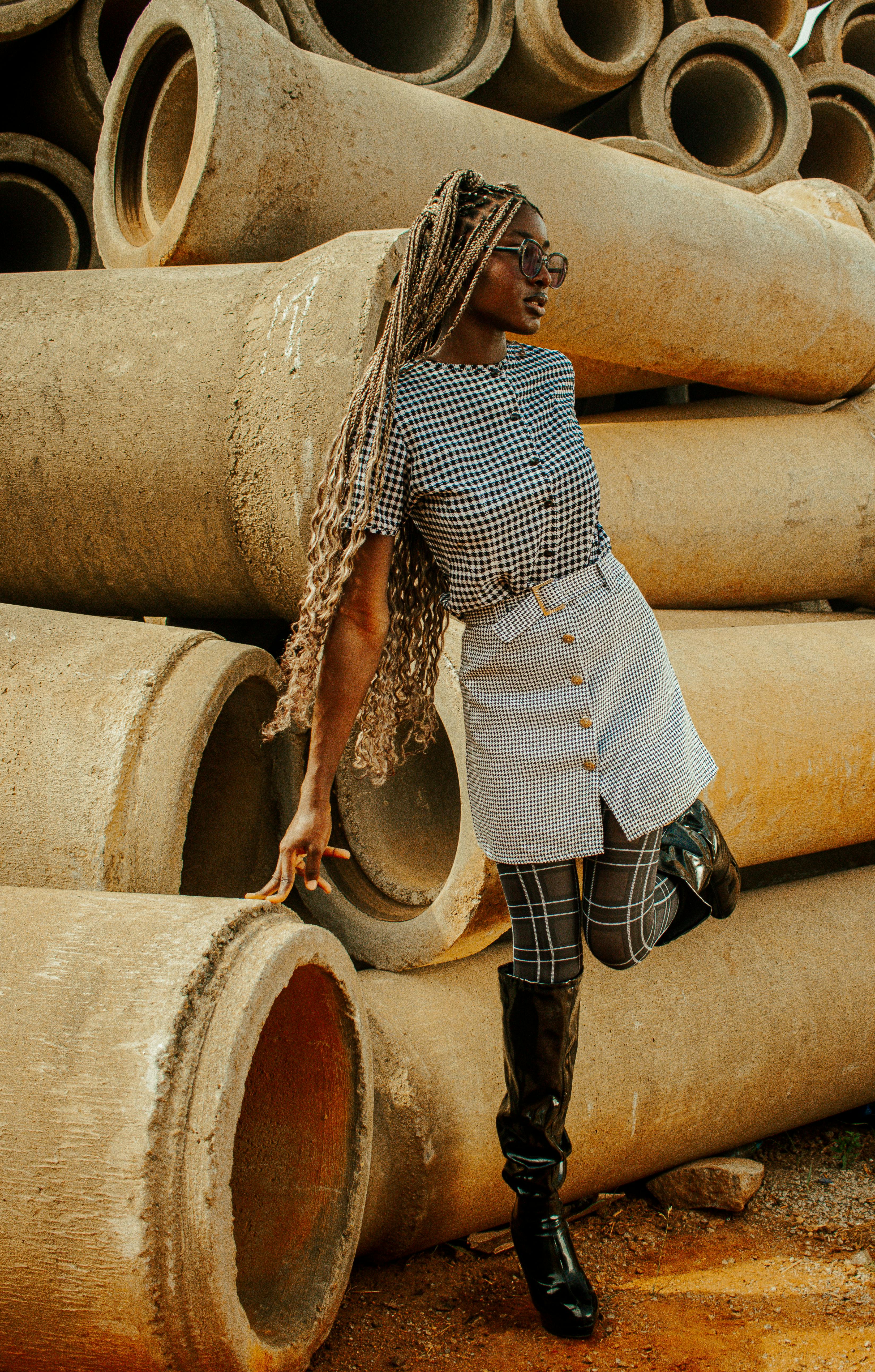 a woman with braided hair wearing a fashionable outfit posing outside