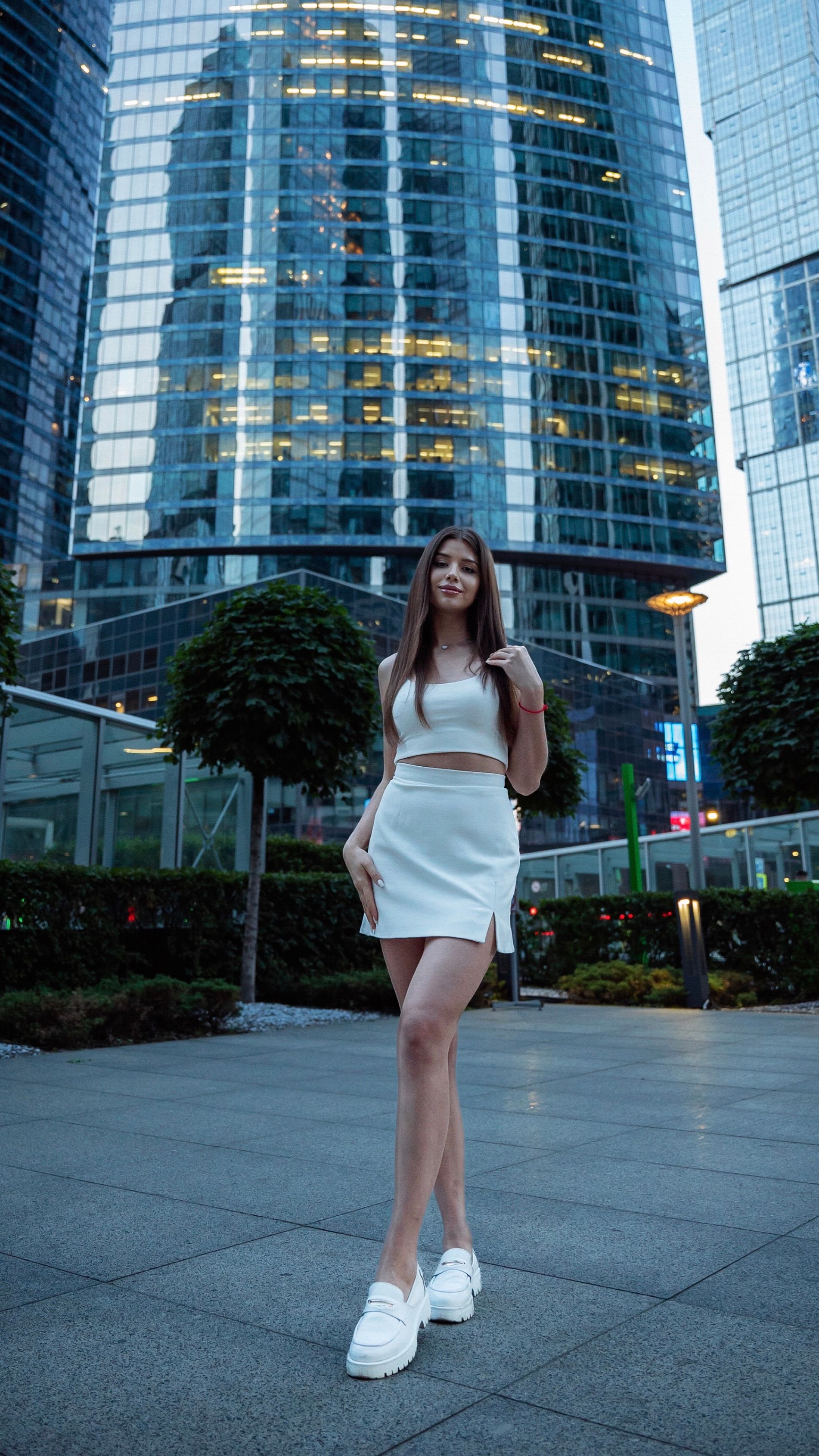 Tall Model in White Crop Top and Mini Skirt at the Foot of a Skyscraper ...