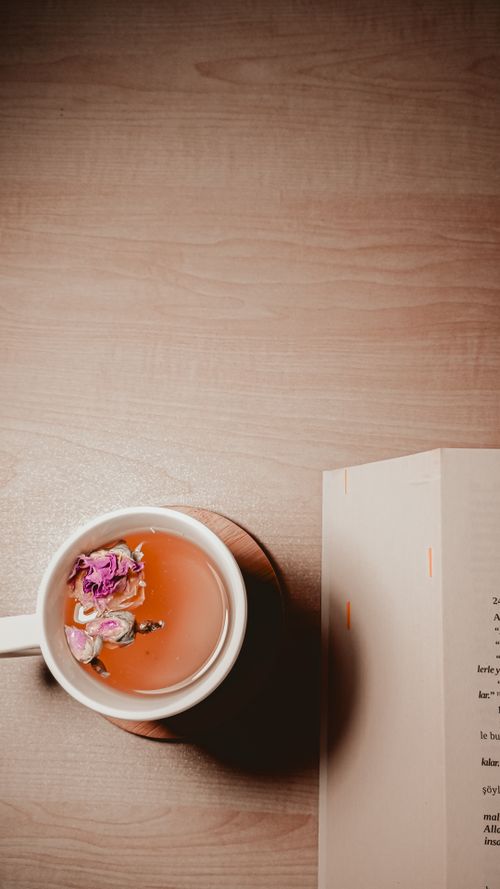 Free A warm flat lay of herbal tea with flowers and an open book on a wooden table. Stock Photo