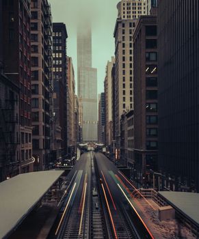 Dramatic view of Chicago's urban cityscape with foggy skyscrapers and vibrant train tracks.