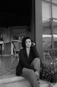 Black and white portrait of a woman sitting in an urban café.