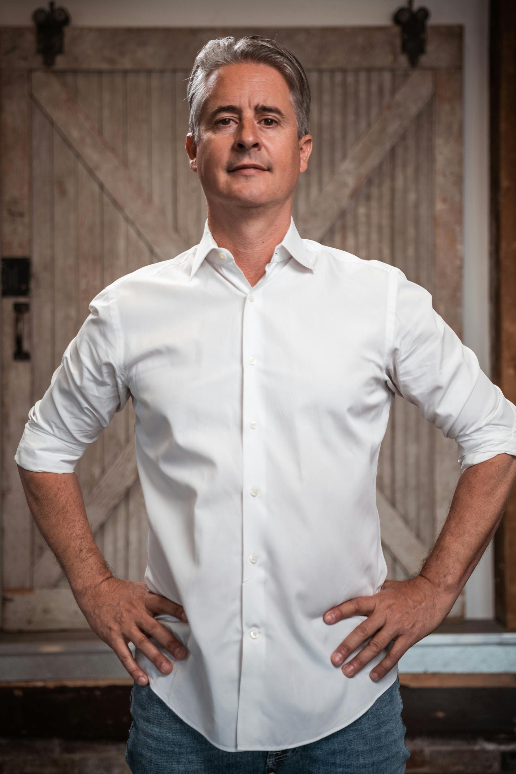Portrait of a confident adult man posing with hands on hips indoors.