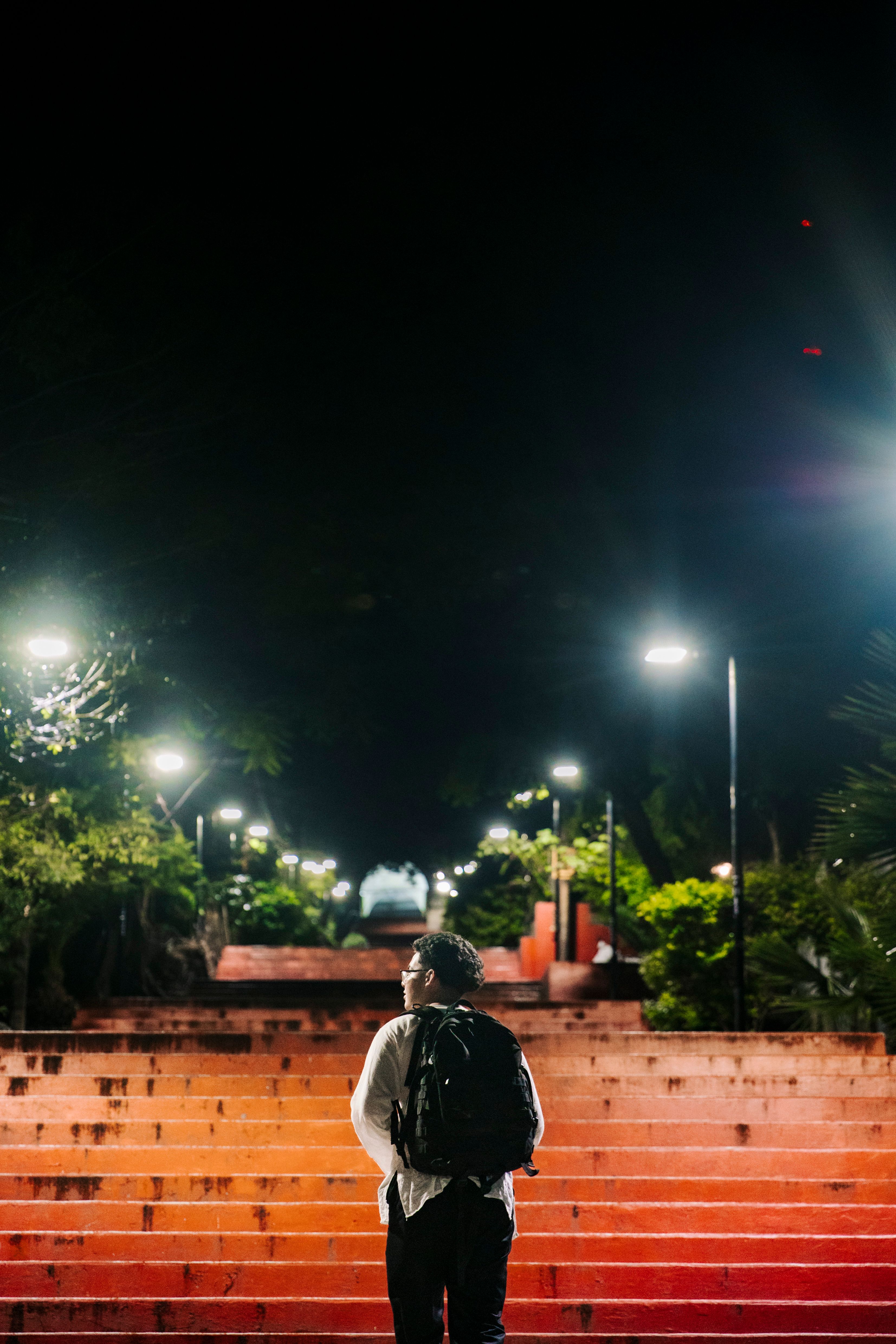Back View of a Man with a Backpack Standing in Front of the Stairs in a ...