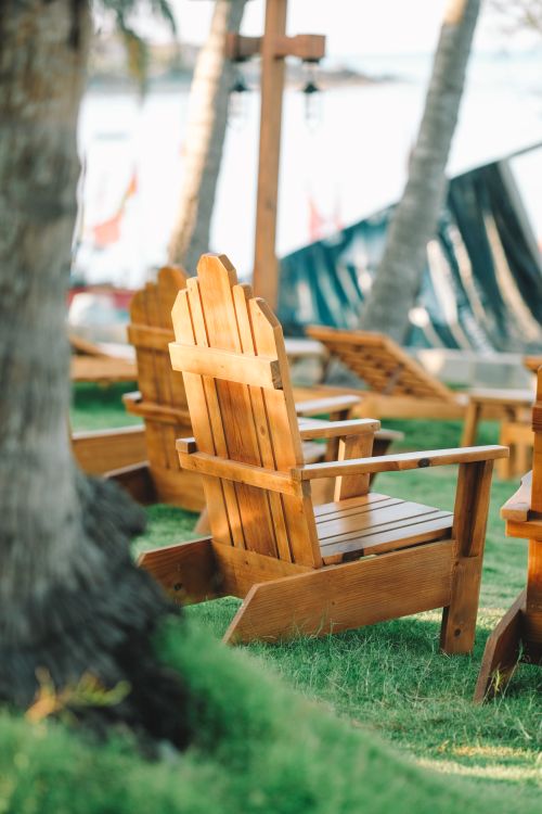Free Rustic wooden chairs on grassy area by a beach in Phan Thiet, Vietnam. Stock Photo