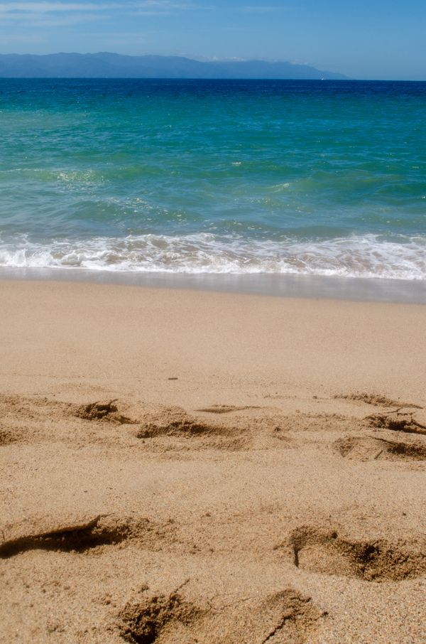 Uma cena costeira tranquila com ondas turquesa claras suavemente batendo nas areias, perfeita para relaxamento.