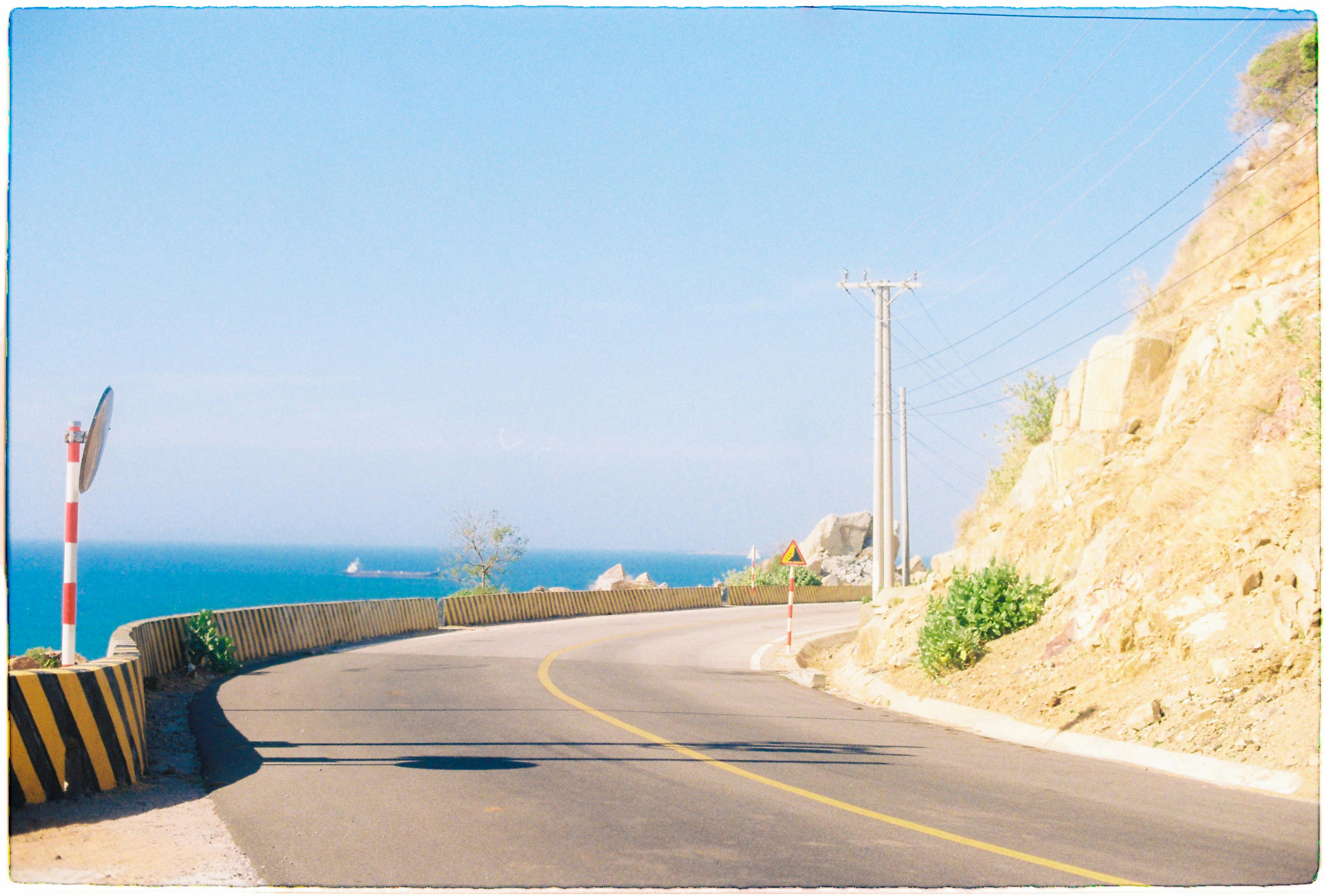 Serene coastal road curve with a clear view of the sea in Ninh Thuận, Vietnam.