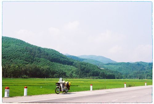 Free A parked motorbike on a rural road against lush green hills in Quang Ngai, Vietnam. Stock Photo