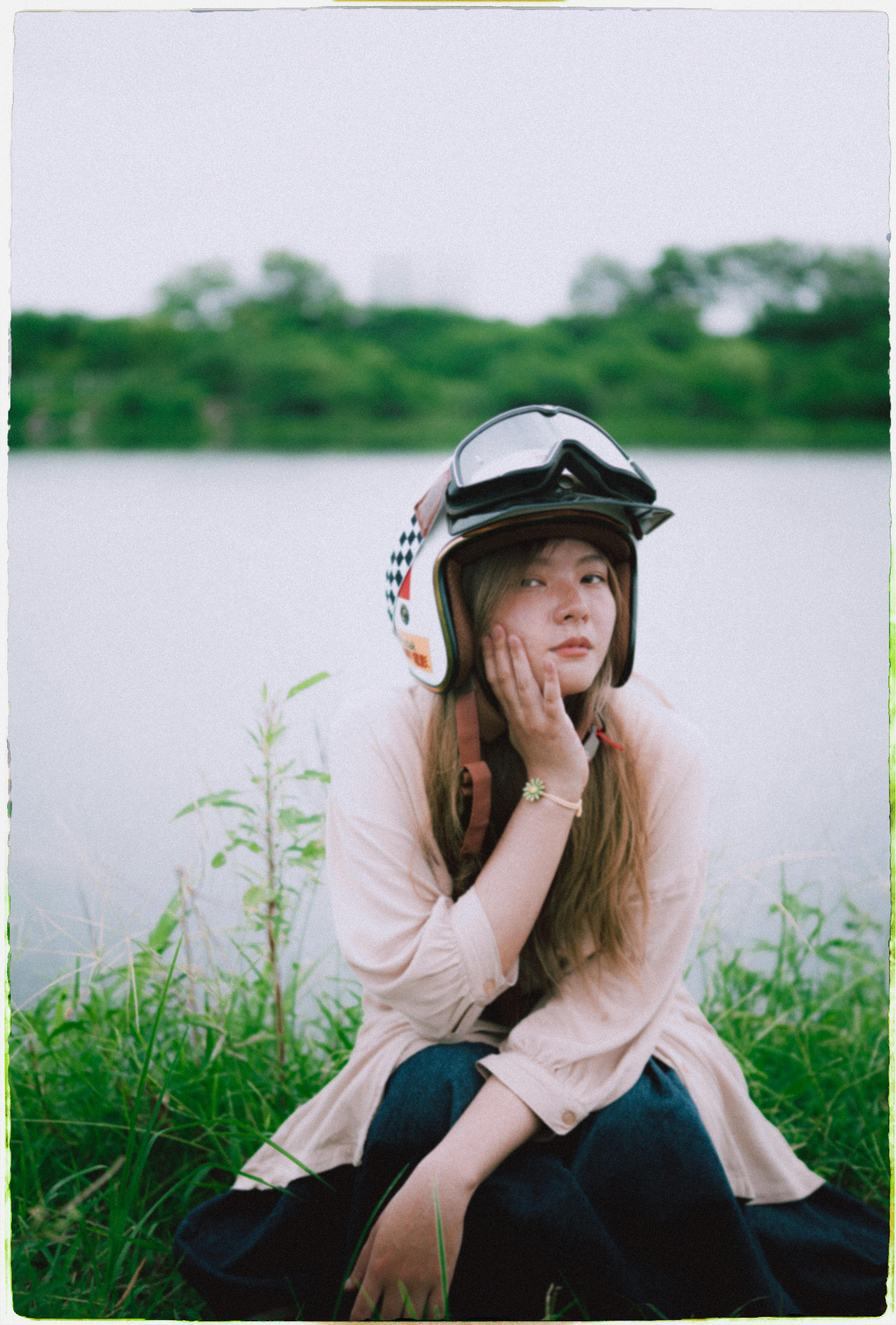 Portrait of a young woman wearing a helmet, sitting lakeside in Ho Chi Minh City.