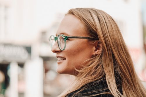 Free Profile of a woman with long hair and eyeglasses, photographed outdoors in a casual, elegant style. Stock Photo