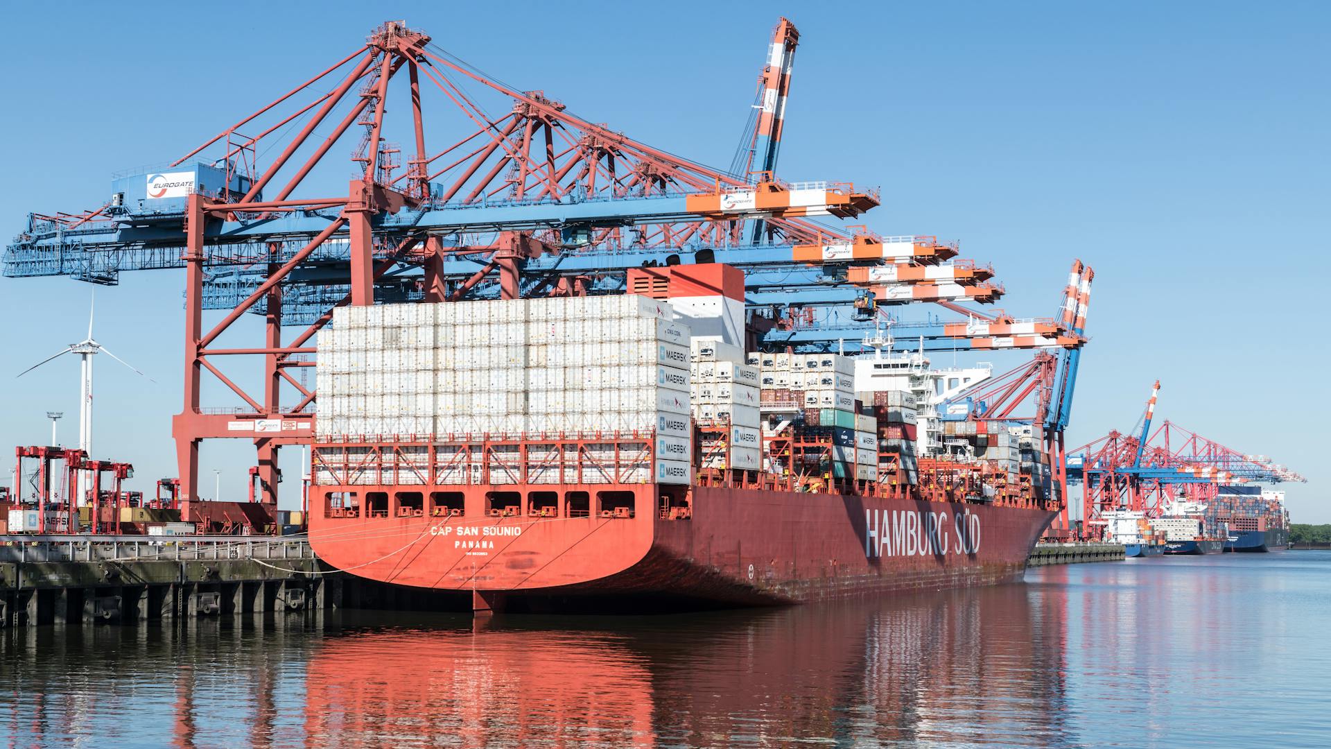 A large container ship docked at Hamburg port with cranes in view, clear day.