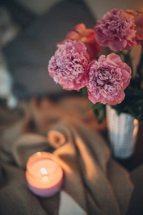 Bezpłatne Zapalona świeca Tealight Obok Kwiatów Zdjęcie z galerii